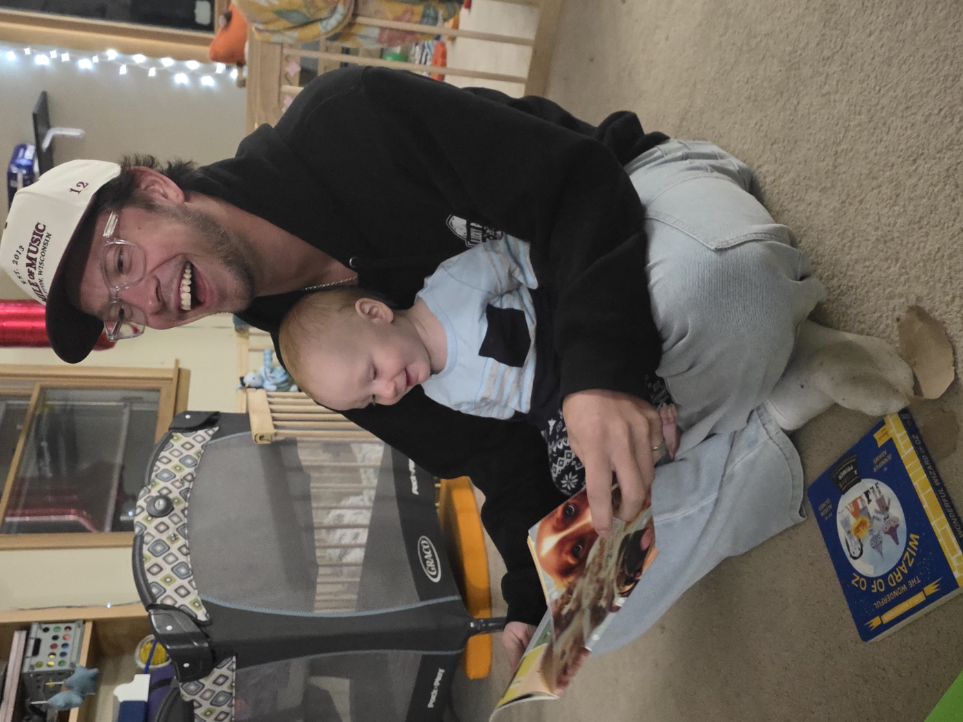 Kadin laughing while reading a picture book with a smiling baby on his lap
